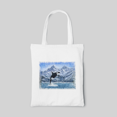 white nature designed tote bag with blue landscape of volcano above water, and a killer whale jumping out of water, front side
