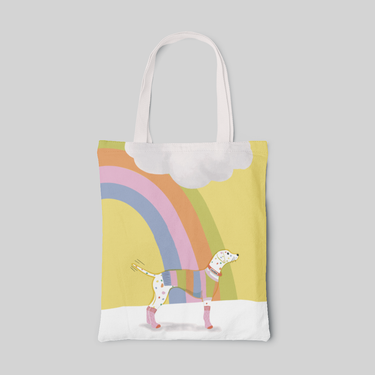 designed white tote bag with rainbow, yellow sky and confetti looking hound in sweater, front side