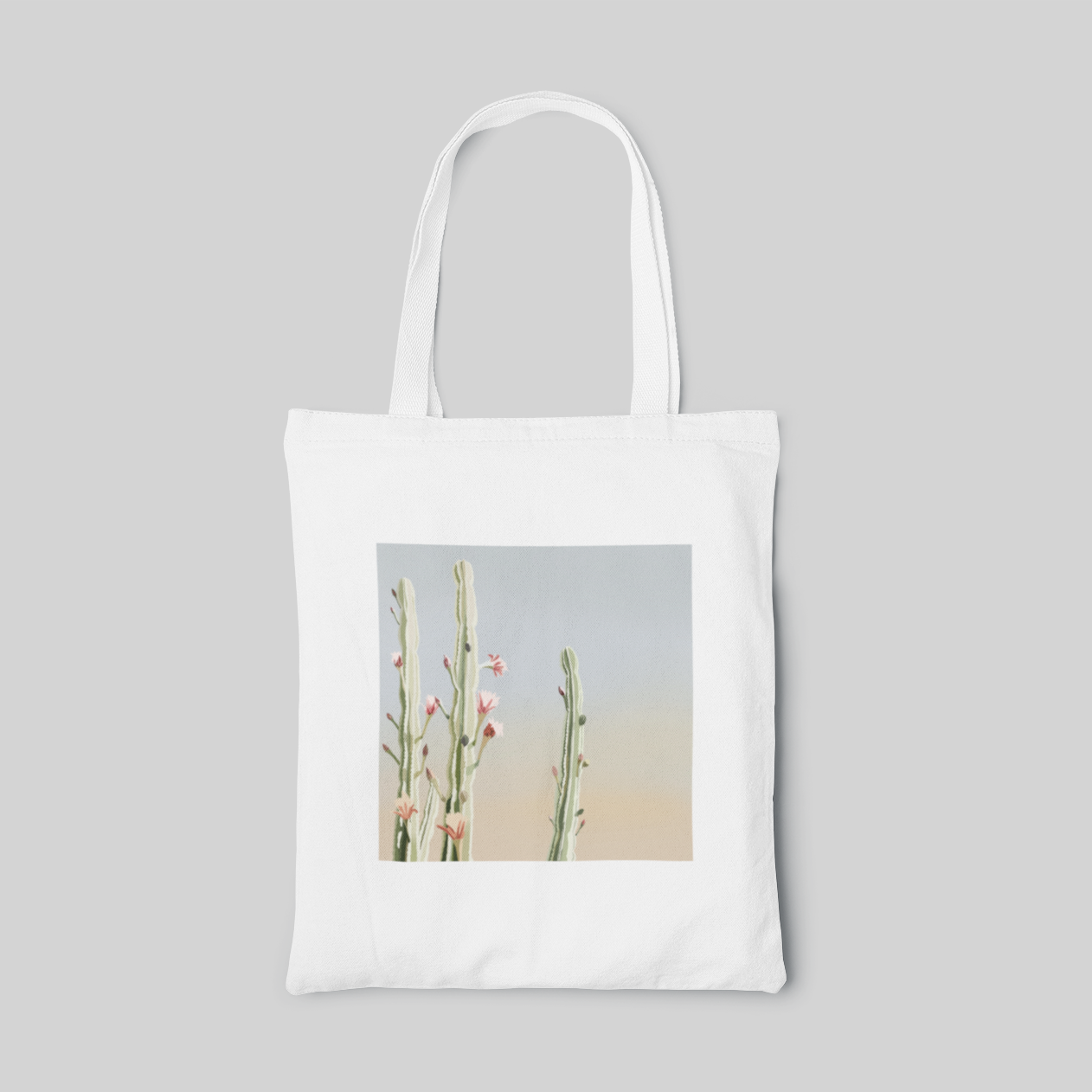 White design tote bag with three cacti in blue to peach ombre background, front side