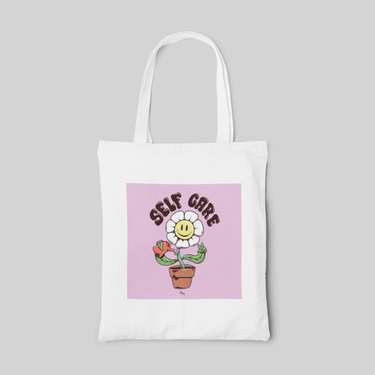White lowbrow designed tote bag with a cartoon sunflower watering itself and self care lettering on purple square, front side